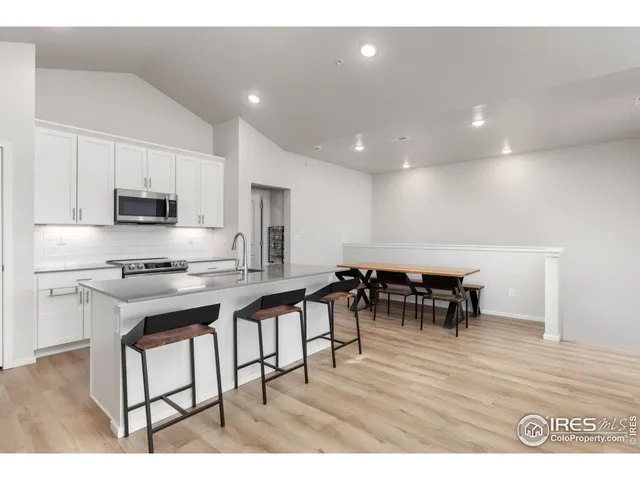 a kitchen with stainless steel appliances kitchen island granite countertop a table chairs and a refrigerator