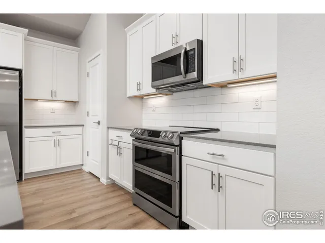 a kitchen with stainless steel appliances white cabinets and a stove a oven with wooden floors