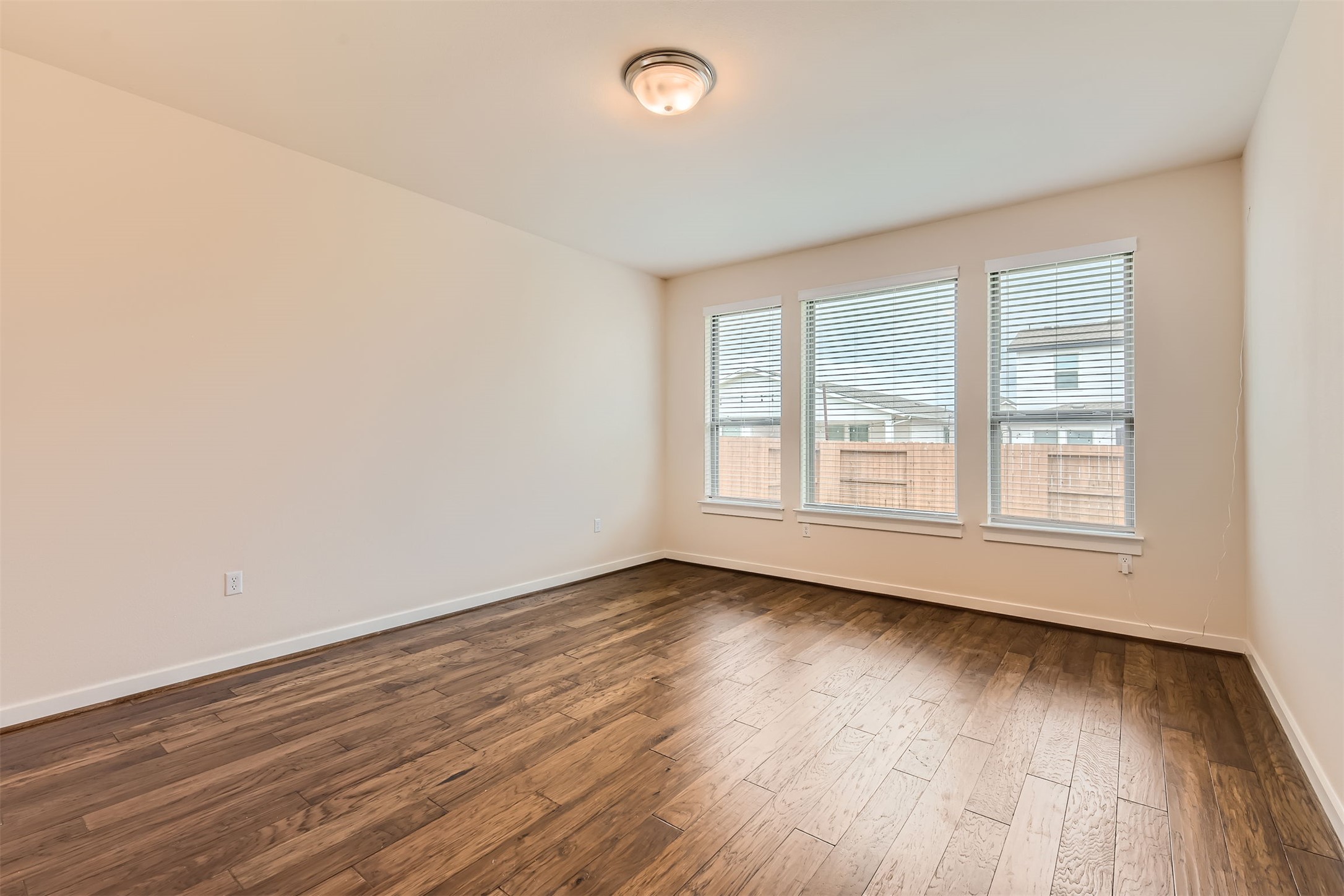 8313 Spire View Austin, TX 78744 - Photo 14 of 33 Rich hardwood flooring complements the naturally illuminated interior through multiple windows, perfect for relaxation or productivity.