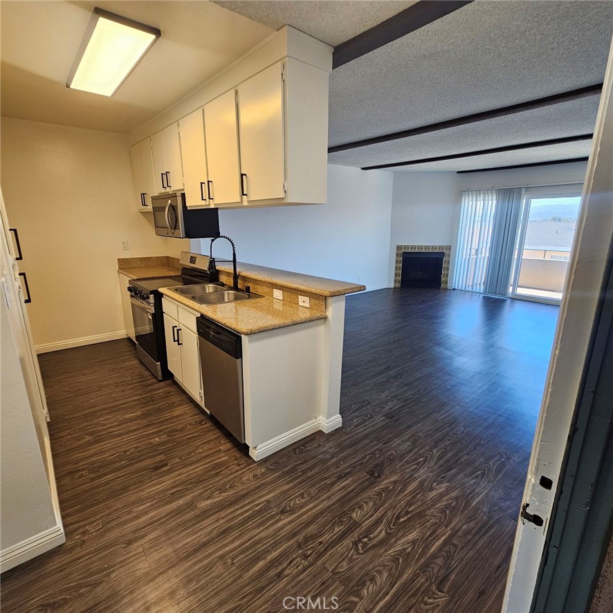 209 South Prospect Avenue, Unit 110 Redondo Beach, CA 90277 - Photo 7 of 11 a kitchen with stainless steel appliances granite countertop a sink stove and wooden floor