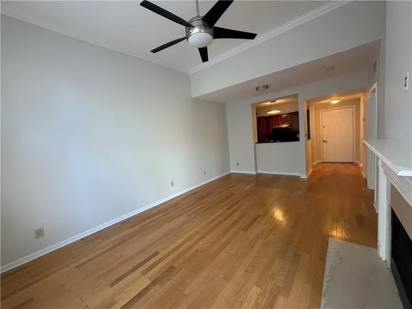 a view of empty room with wooden floor and fan