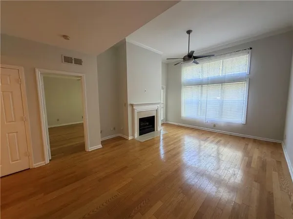 a view of a livingroom with a fireplace a ceiling fan and wooden floor