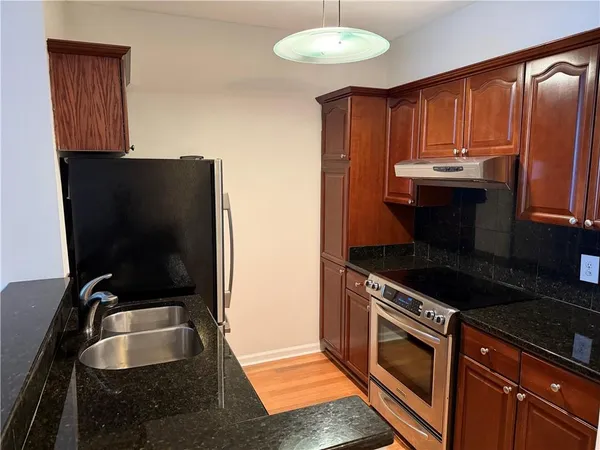 a kitchen with granite countertop a sink stove and cabinets