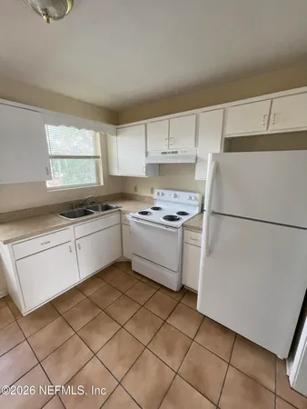 a kitchen with a cabinets a sink and white appliances