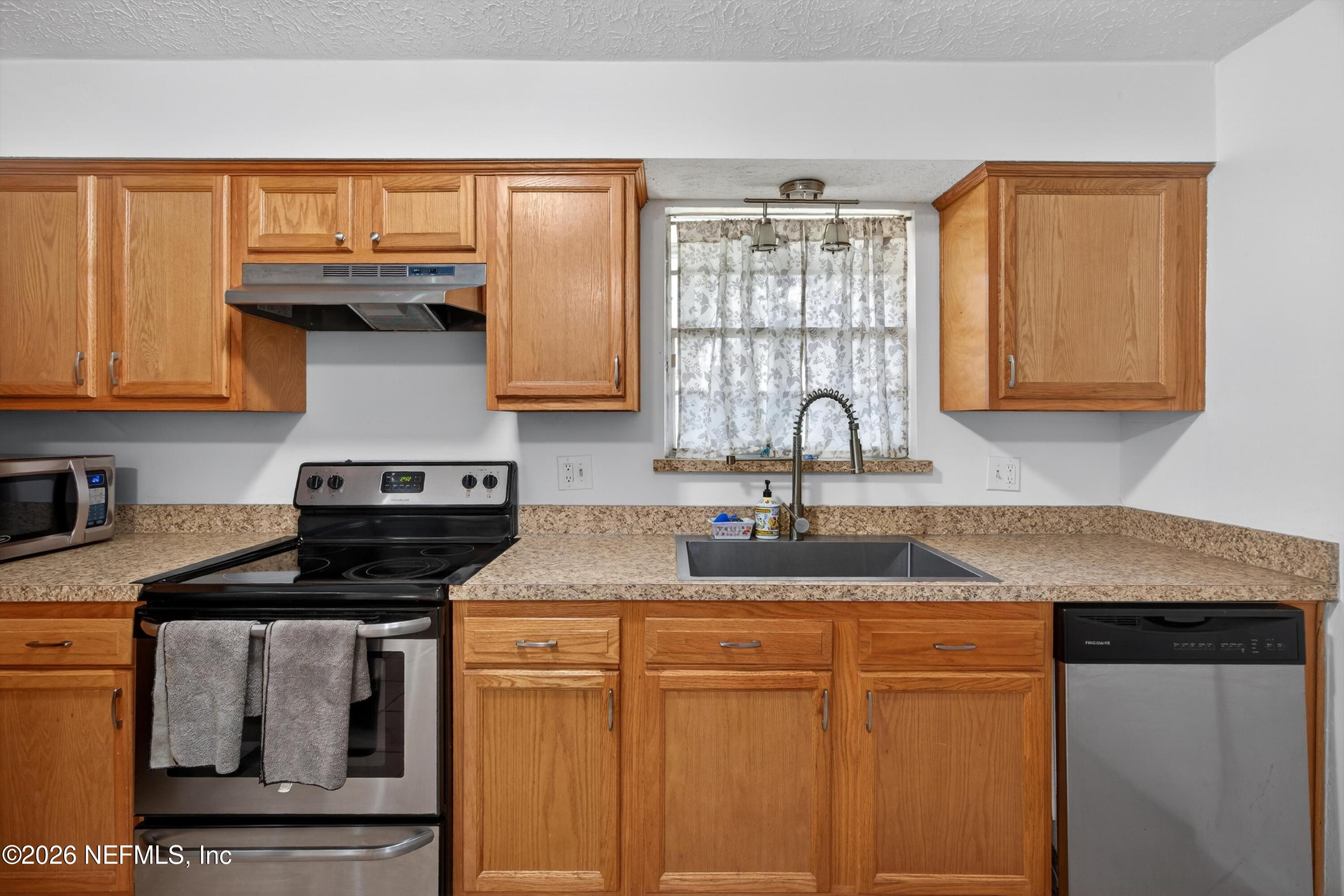 3570 Grassy Ride Drive Jacksonville, FL 32223 - Photo 18 of 51 a kitchen with granite countertop a sink a stove and cabinets