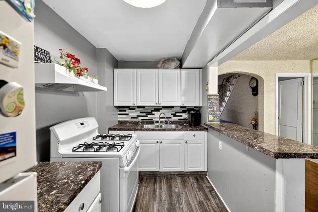 a kitchen with granite countertop a sink stove and refrigerator
