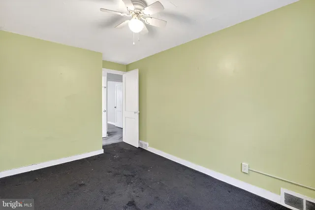an empty room with a ceiling fan and carpet