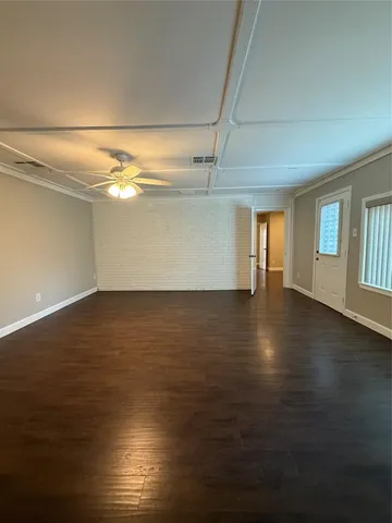 an empty room with wooden floor and windows with curtains
