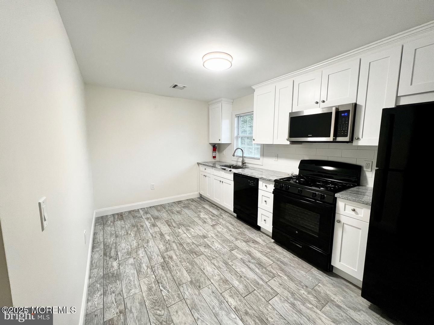 1253 Yardville Allentown Road, Unit 2 Allentown, NJ 08501 - Photo 4 of 12 a kitchen with stainless steel appliances a stove top oven a sink a refrigerator white cabinets and wooden floor
