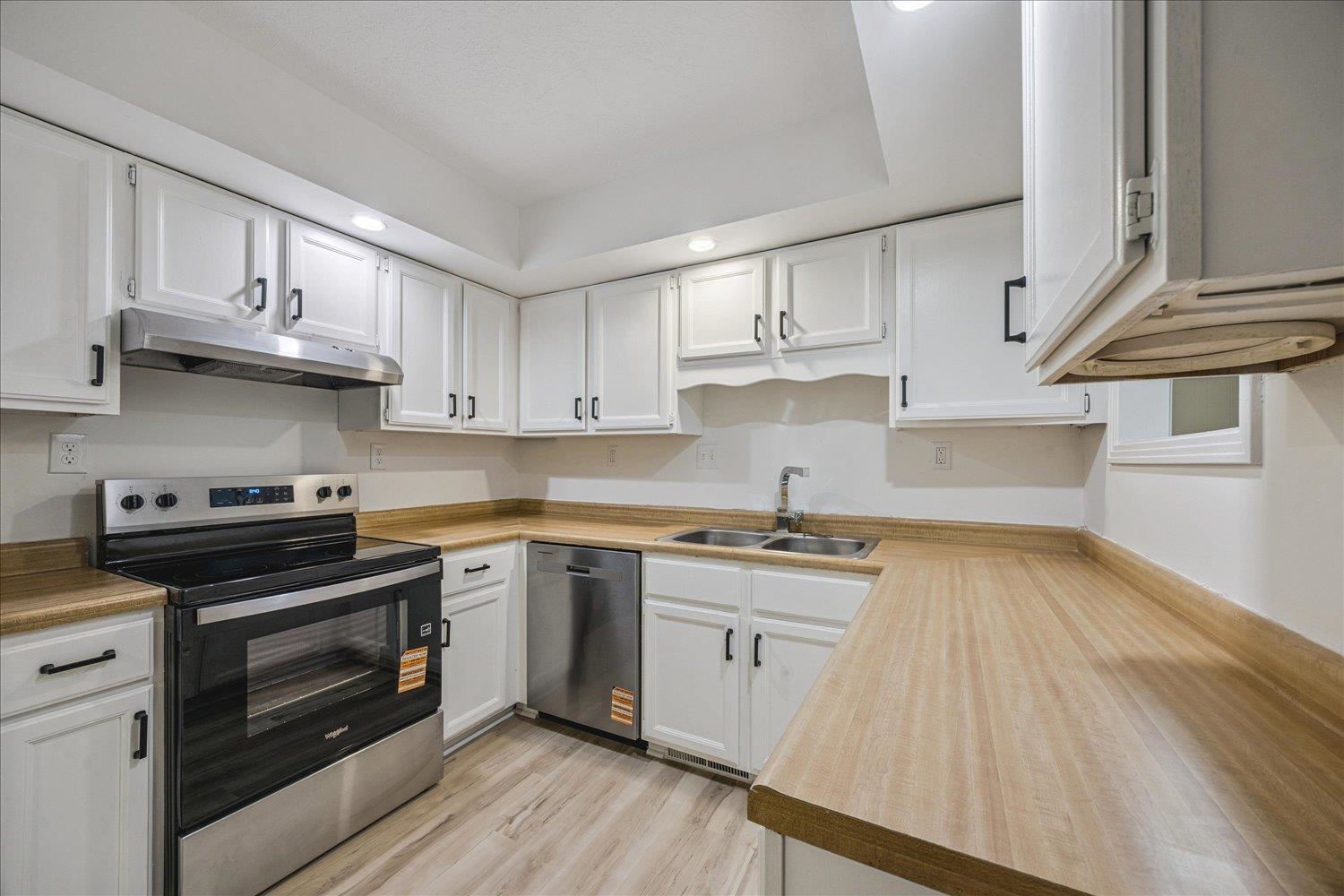 6137 Quince Road Memphis, TN 38119 - Photo 8 of 19 Kitchen with stainless steel appliances, white cabinetry, light wood finished floors, recessed lighting, and light countertops