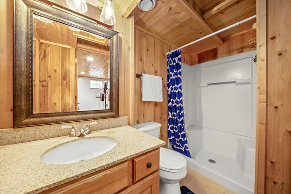 a bathroom with a granite countertop sink toilet mirror and shower