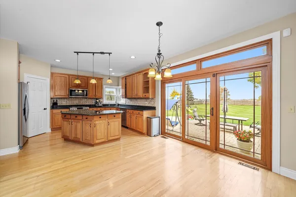a large kitchen with stainless steel appliances kitchen island granite countertop a refrigerator a oven a stove and a wooden floors