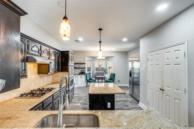 a large kitchen with a table chairs stainless steel appliances and cabinets