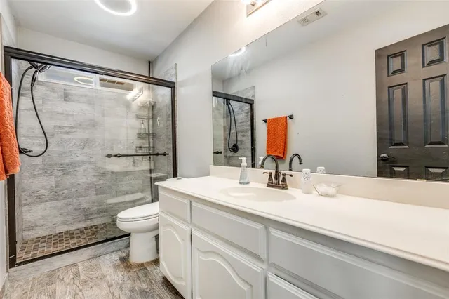 a bathroom with a double vanity sink toilet mirror and shower