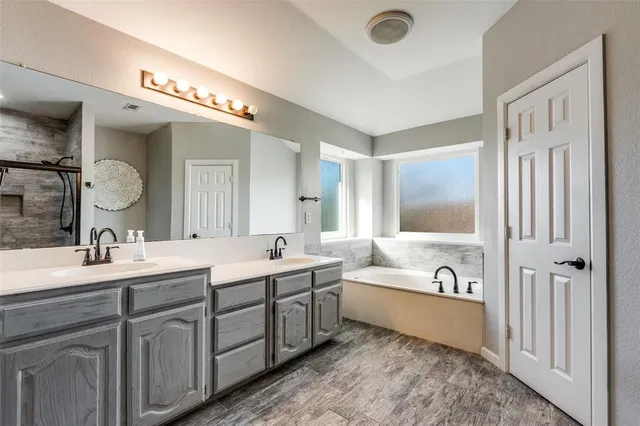 a spacious bathroom with a double vanity sink mirror and bathtub