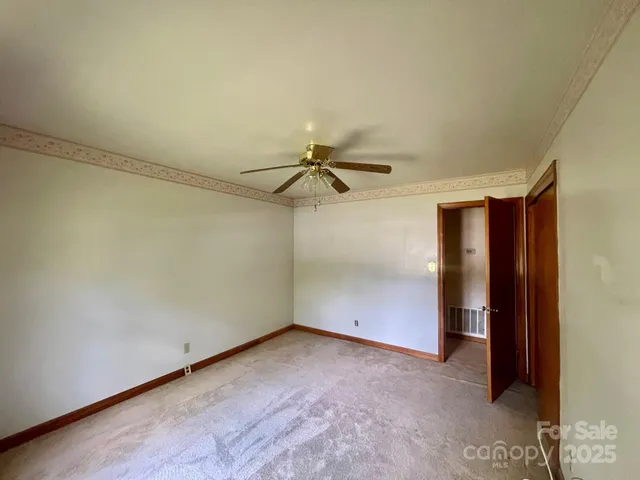 an empty room with a ceiling fan and carpet