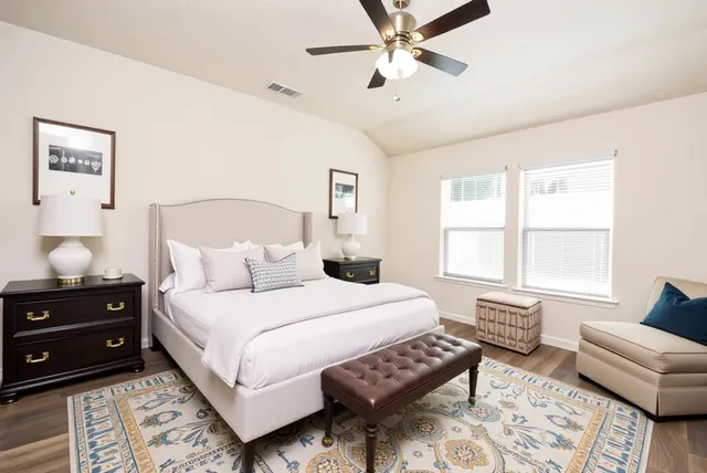 an empty room with wooden floor chandelier fan and windows