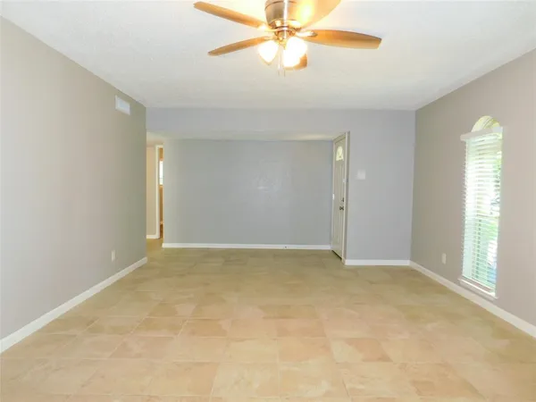 an empty room with windows and fan