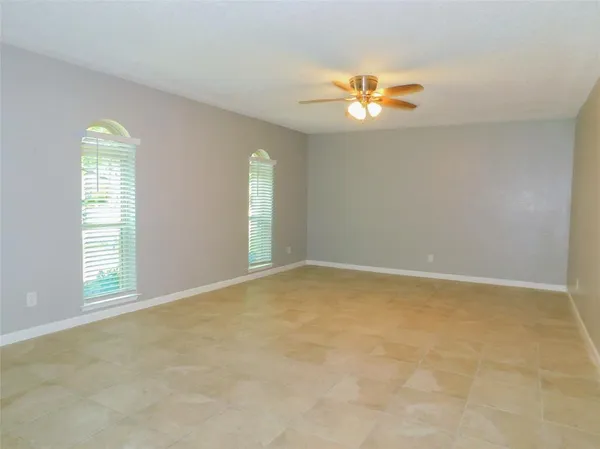 an empty room with windows and chandelier fan