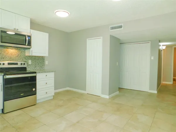 a view of a kitchen with white cabinets and stainless steel appliances
