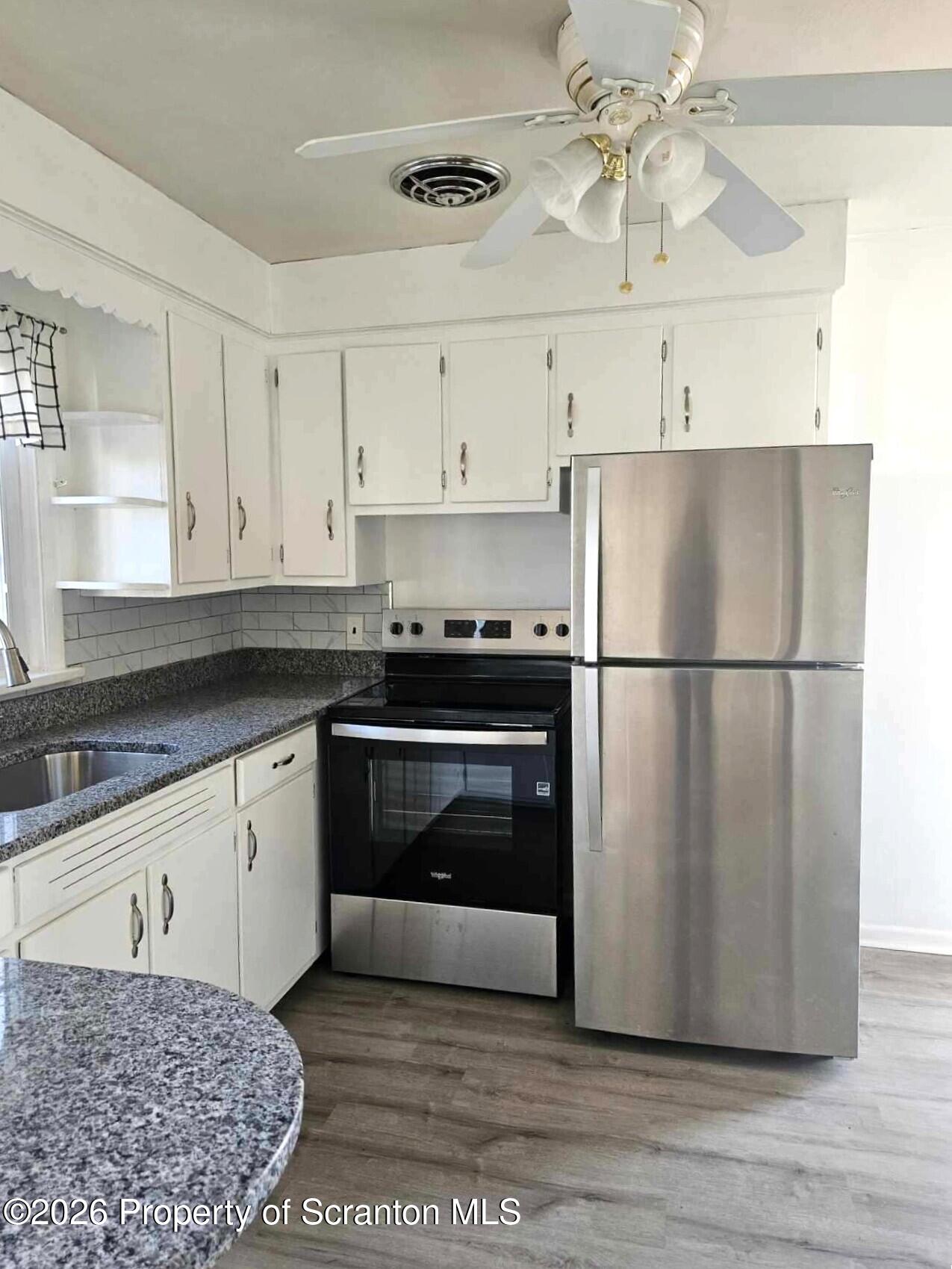 133 Corcoran Street Old Forge, PA 18518 - Photo 3 of 15 a kitchen with granite countertop a refrigerator a stove a microwave and cabinets