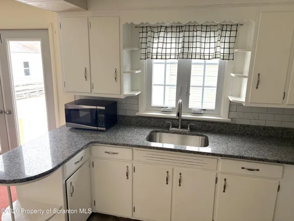 a kitchen with granite countertop a sink a refrigerator and window