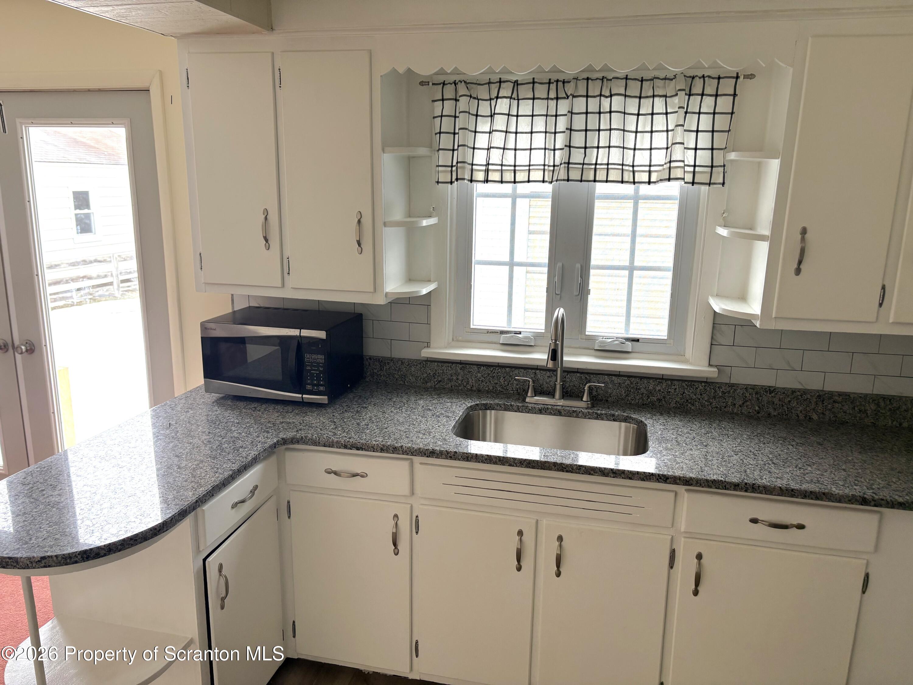 133 Corcoran Street Old Forge, PA 18518 - Photo 4 of 15 a kitchen with granite countertop a sink a refrigerator and window