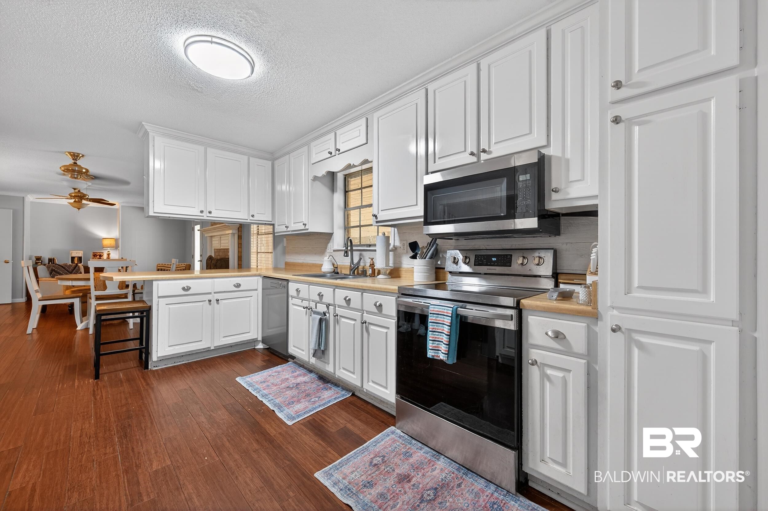 46006 Pecan Lane Bay Minette, AL 36507 - Photo 11 of 40 Kitchen with light countertops, stainless steel appliances, white cabinetry, a peninsula, and dark wood-type flooring
