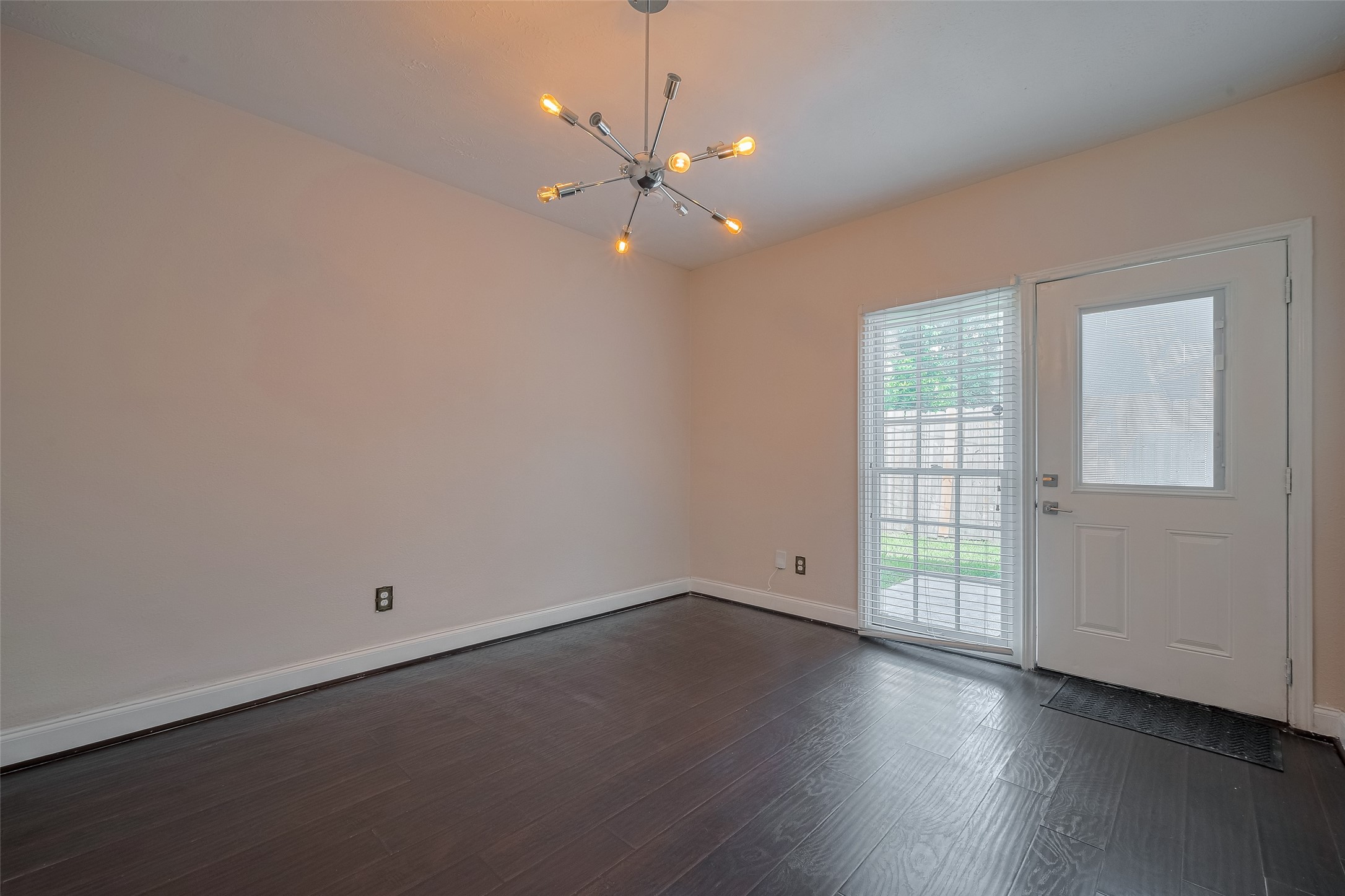 3930 Daphne Street Houston, TX 77021 - Photo 12 of 44 The dining area seamlessly connects to the kitchen, anchored by a tall window and glass paneled door that leads out to the patio—elevated by a sculptural chandelier that adds a touch of modern flair.