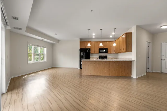a view of kitchen with kitchen island wooden floor center island and stainless steel appliances