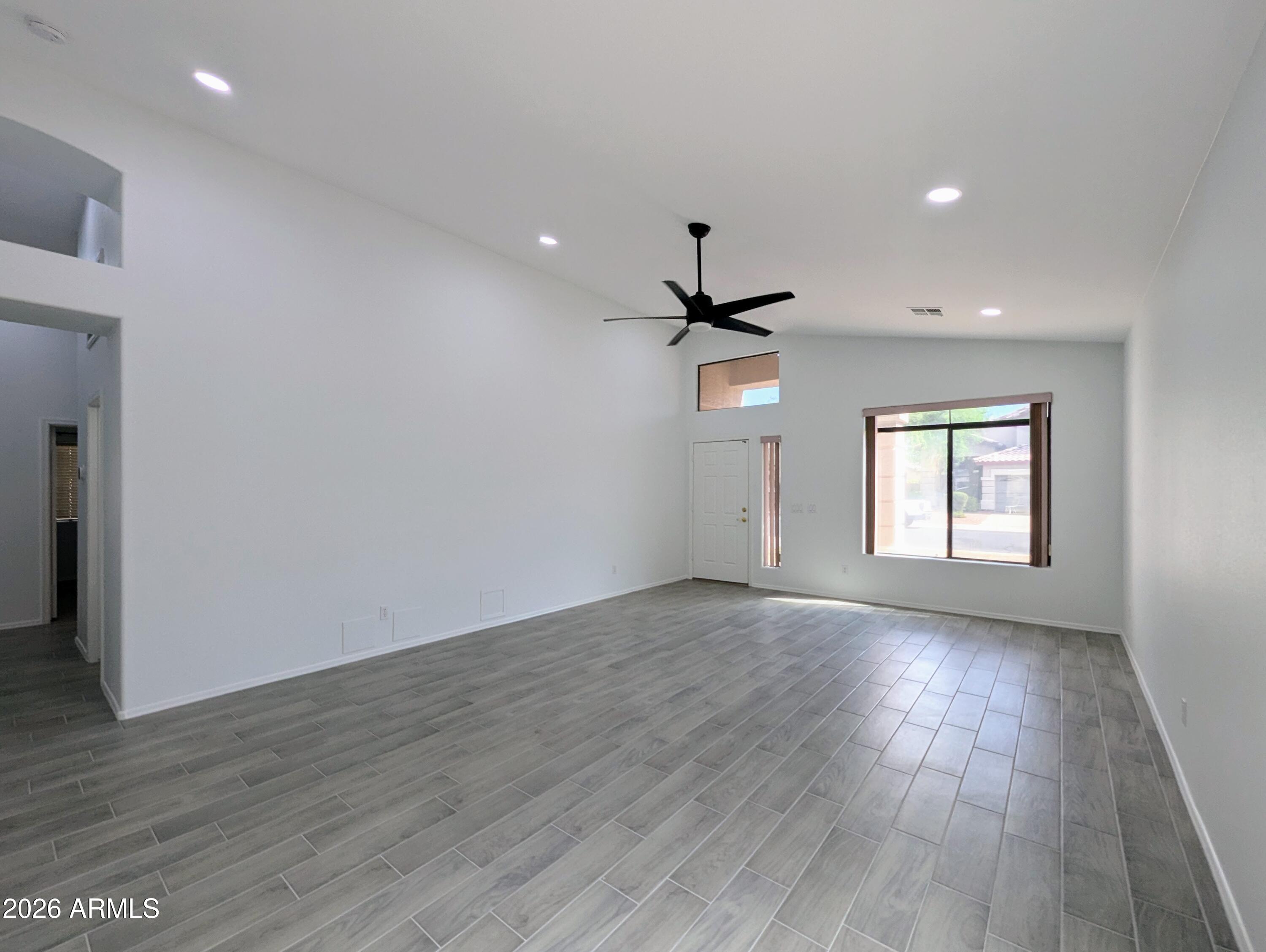 5424 West Wagoner Road Glendale, AZ 85308 - Photo 7 of 37 an empty room with wooden floor ceiling fan and windows