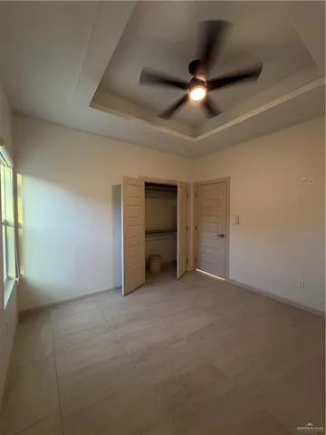 an empty room with a ceiling fan and windows