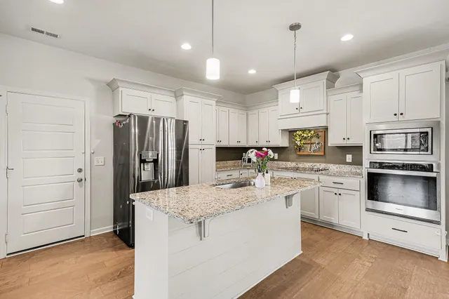 a kitchen with kitchen island granite countertop a stove cabinets and refrigerator