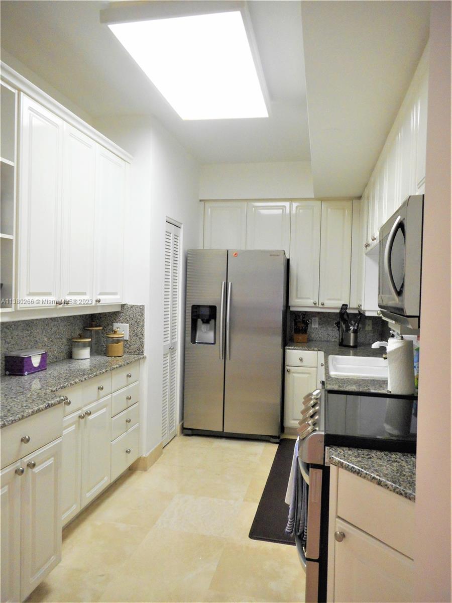 888 Brickell Key Drive, Unit 511 Miami, FL 33131 - Photo 19 of 26 a kitchen with white cabinets and stainless steel appliances
