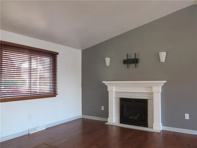 a view of an empty room with a fireplace and a window