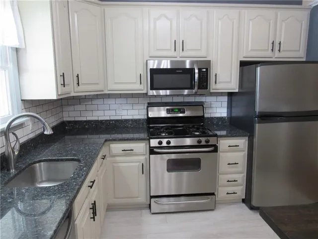 a kitchen with white cabinets and stainless steel appliances
