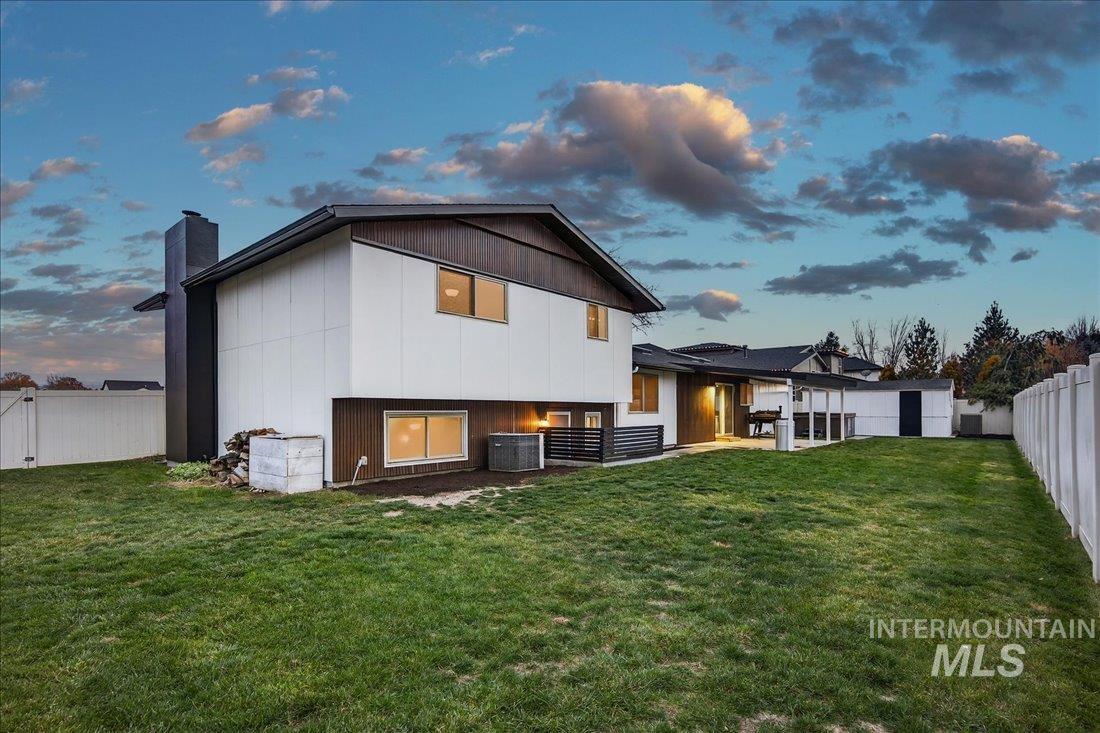 4393 North Edelweiss Street Boise, ID 83713 - Photo 35 of 42 Back of house at dusk featuring a fenced backyard, a chimney, and a patio