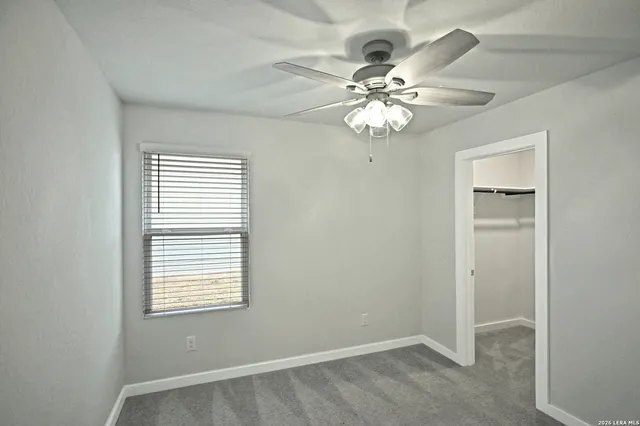 an empty room with windows and fan