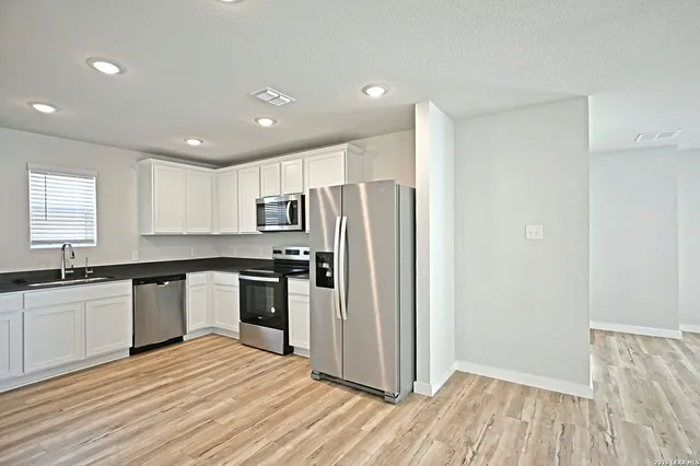 a kitchen with stainless steel appliances granite countertop a refrigerator and a stove top oven