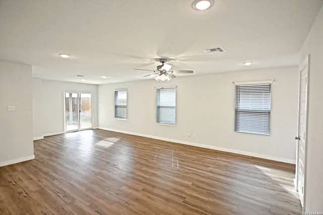 a view of an empty room with wooden floor and a window