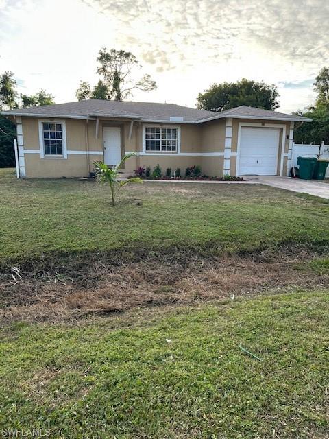 Ranch-style home with stucco siding, a garage, a front lawn, and concrete driveway