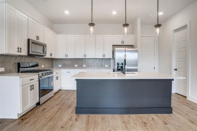 a kitchen with stainless steel appliances granite countertop a sink a stove and a refrigerator