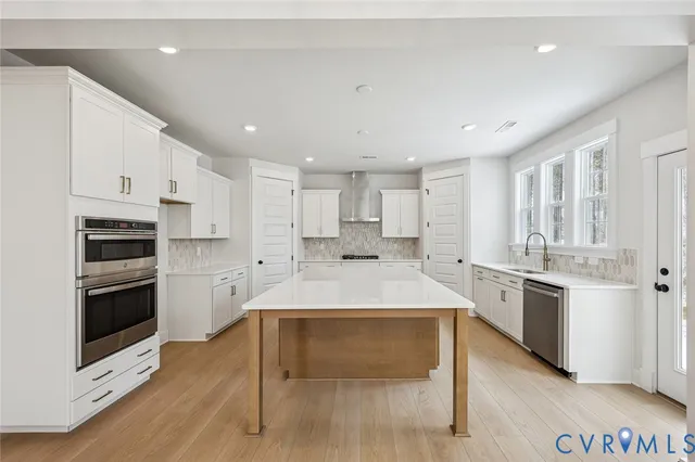 a large white kitchen with kitchen island a sink appliances and cabinets