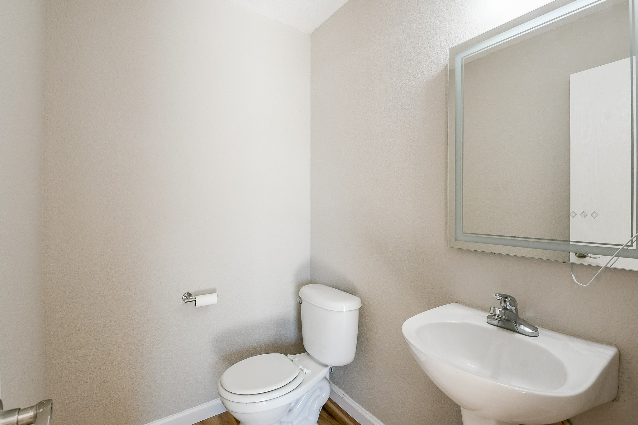 20807 Lansing Ridge Lane Katy, TX 77449 - Photo 16 of 35 This is a small, modern half-bathroom with neutral walls, featuring a toilet, a pedestal sink, and a wall-mounted mirror.