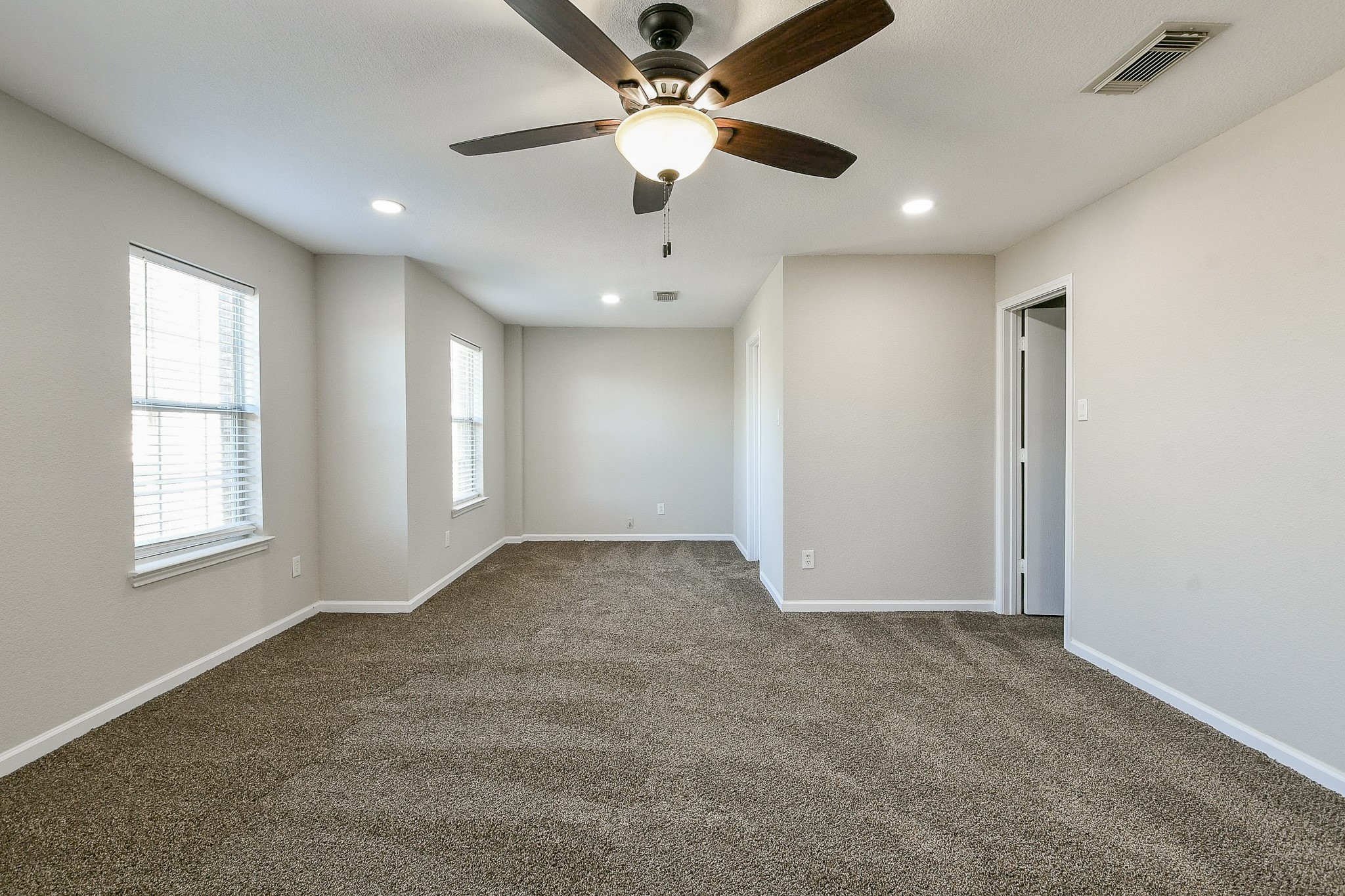 20807 Lansing Ridge Lane Katy, TX 77449 - Photo 25 of 35 This spacious, carpeted room features neutral walls, a ceiling fan with lighting, and multiple windows for natural light, making it perfect for a cozy living area or bedroom.