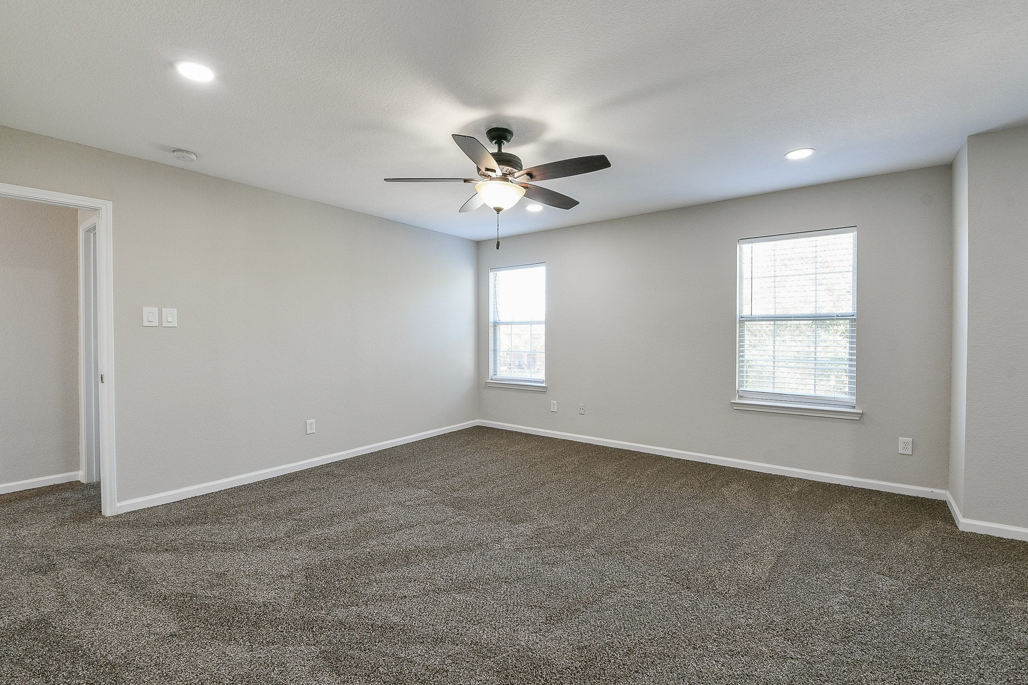 20807 Lansing Ridge Lane Katy, TX 77449 - Photo 28 of 35 This spacious bedroom features neutral walls, plush carpeting, and ample natural light from two windows. It includes a ceiling fan with light, creating a comfortable and inviting atmosphere.