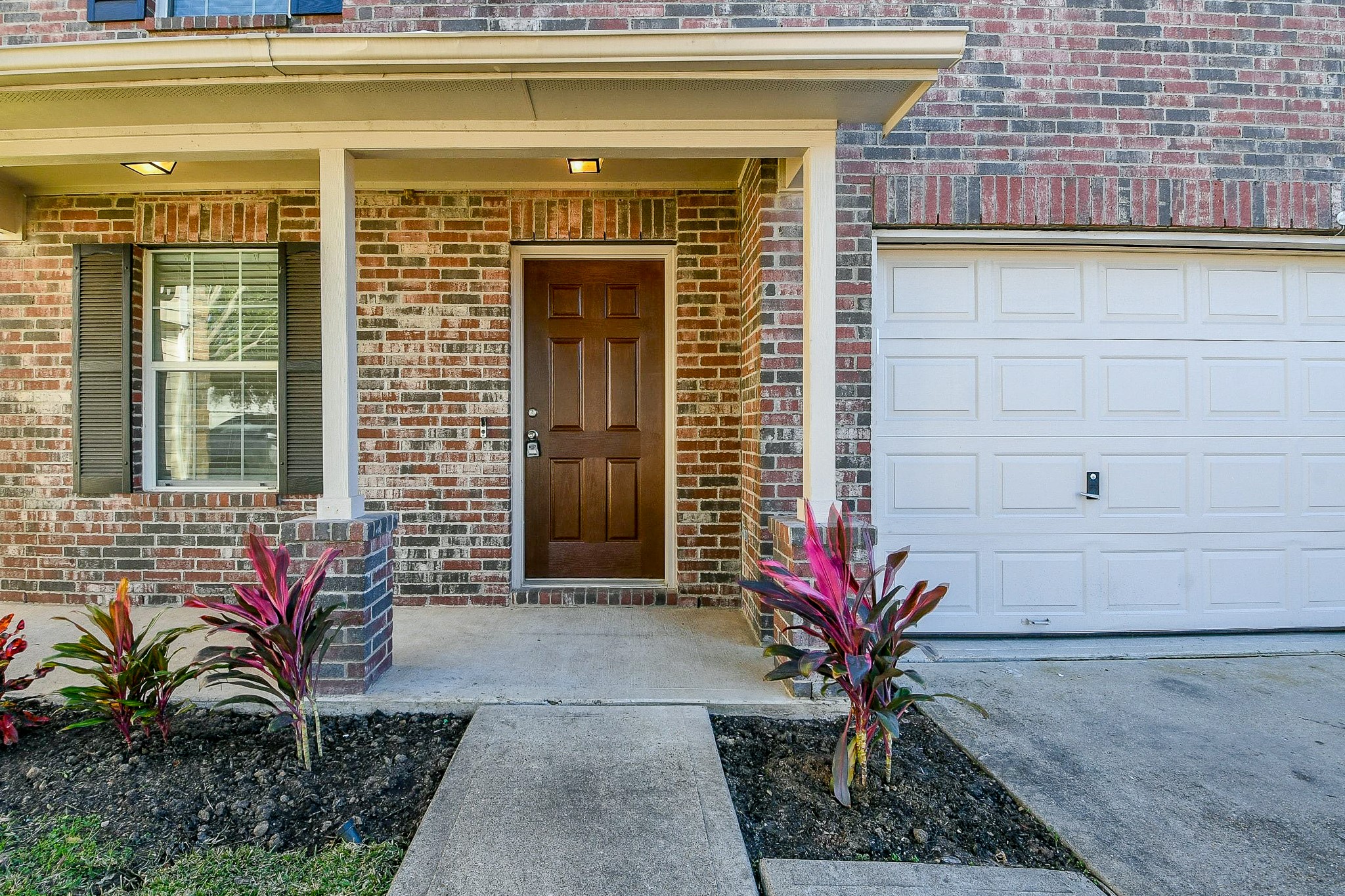 20807 Lansing Ridge Lane Katy, TX 77449 - Photo 3 of 35 Charming brick exterior with a welcoming front porch, featuring a solid wood door and attractive landscaping. Adjacent is a spacious garage with a clean, white door. Perfect for curb appeal.