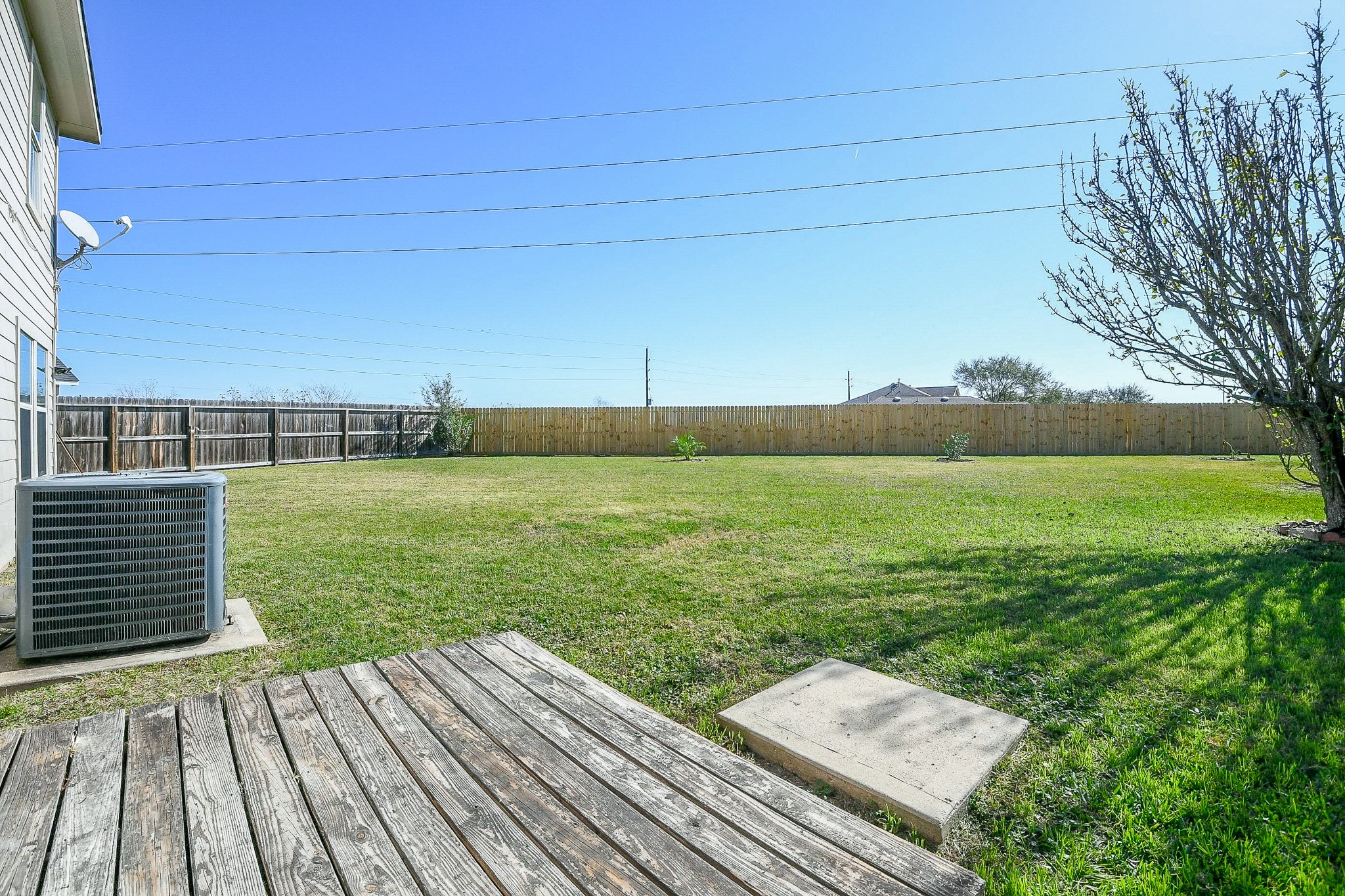 20807 Lansing Ridge Lane Katy, TX 77449 - Photo 31 of 35 Spacious backyard with well-maintained lawn, wooden deck, and privacy fence. Ideal for outdoor activities and relaxation.