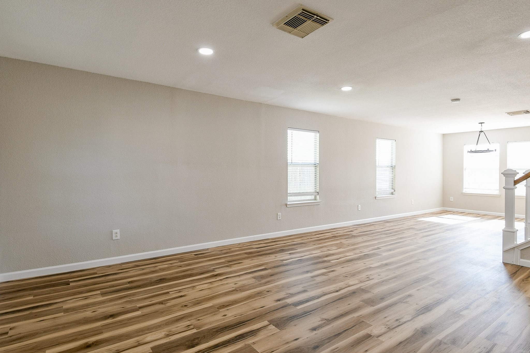20807 Lansing Ridge Lane Katy, TX 77449 - Photo 6 of 35 This photo showcases a spacious, well-lit room with light wood flooring and neutral-colored walls. It features several windows allowing natural light, recessed lighting, and a visible staircase leading to another level.
