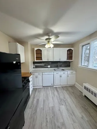 a large kitchen with cabinets wooden floor and stainless steel appliances